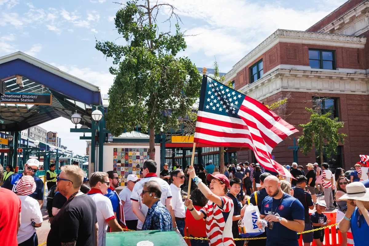 A young fan waves an American flag above a crowd outside International District/Chinatown light rail station