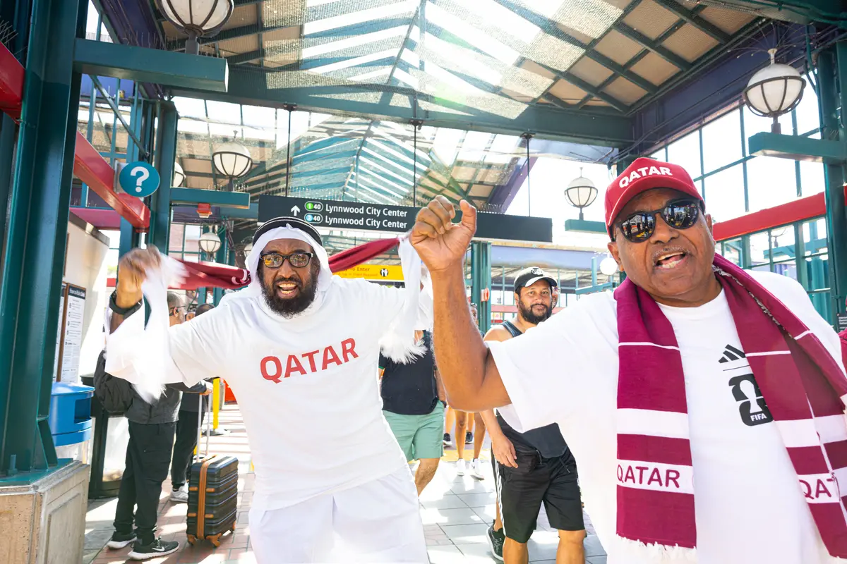 Two Qatar fans cheer as they exit International District/Chinatown Station on their way to the Qatar match in Seattle